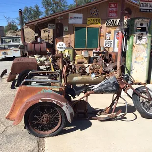 a rusted motorcycle parked in front of a gas station