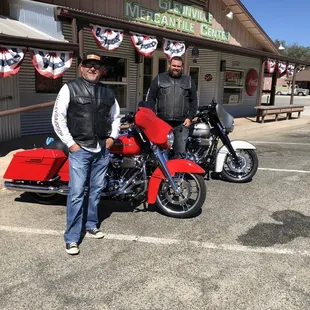 two men standing next to motorcycles