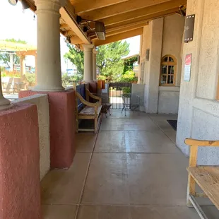 a porch with a bench and chairs