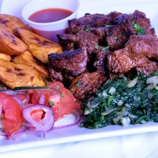 Nyama choma (grilled beef), plantains, kachumbari, and spinach