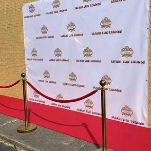 a red carpet and a white backdrop