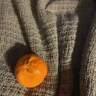 a single orange on a blanket
