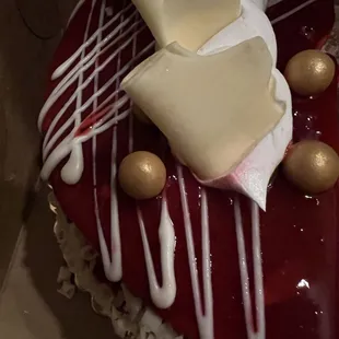 a red cake with white icing and nuts