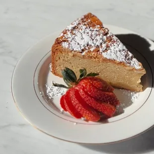a slice of cake with powdered sugar and strawberries
