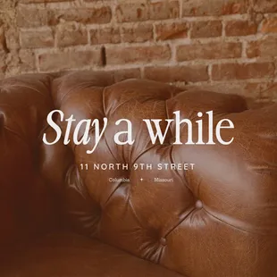 a brown leather couch with a brick wall in the background