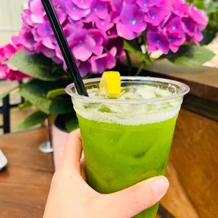 a hand holding a green drink