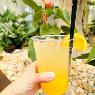a hand holding a glass of orange juice