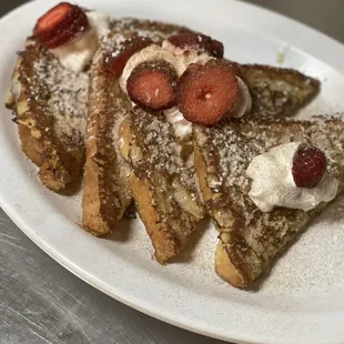 a plate of french toast with strawberries and whipped cream