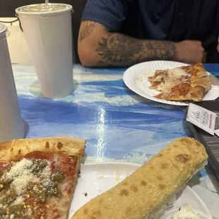 Combo place with two bread sticks and a slice of pizza with pepperoni and green Chile.