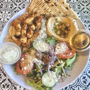 Chicken shawarma on  bed of rice with a side of greek salad and Hummus