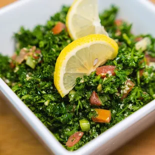 a bowl of kale salad with lemon slices