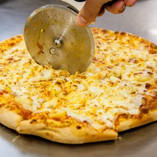 a pizza being sliced with a pizza cutter