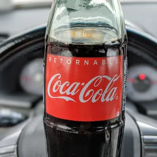 a hand holding a bottle of coke