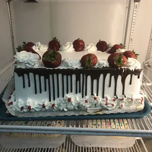 a cake with chocolate drips and strawberries