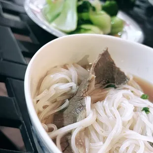 a bowl of noodles with beef and broccoli