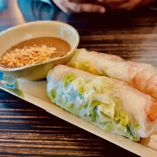 a plate of rice rolls and a bowl of dipping sauce