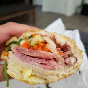 a hand holding a half eaten sandwich