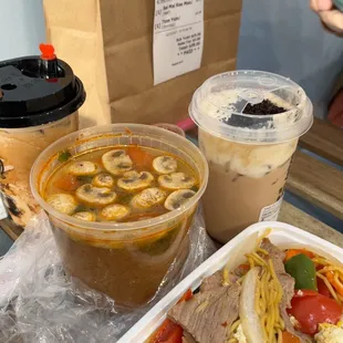 two containers of soup and a sandwich