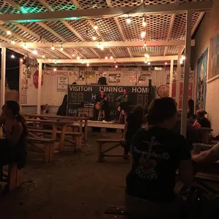 people sitting at tables under a pergolated roof