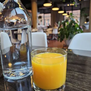 a glass of orange juice and a bottle of water