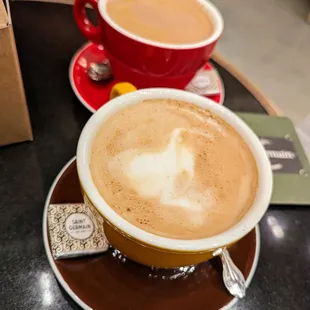 Latte. $6.75. Hot, English Toffee ($0.75), Oat Milk ($0.75). In the back is a Mocha. $5.75. Hot, Oat Milk ($0.75).