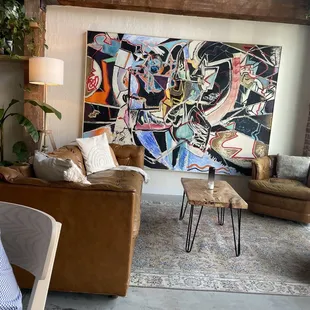 a living room with couches and a painting on the wall