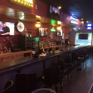a bar with bar stools and televisions