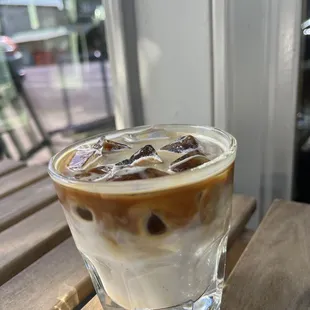 a glass of iced coffee on a wooden table