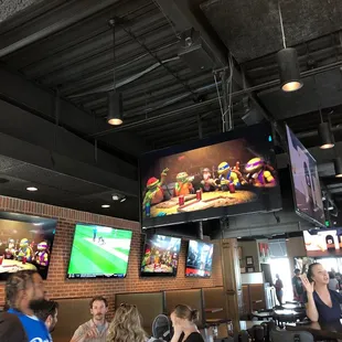 people sitting at tables and watching tvs