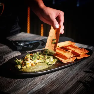 a hand dipping a tortilla