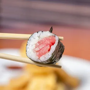 a piece of sushi being held by chopsticks