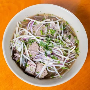 a bowl of beef noodle soup on a wooden table