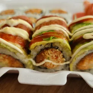 a variety of sushi rolls in a styrofoam container