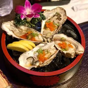 a plate of oysters with a side of lemon wedges