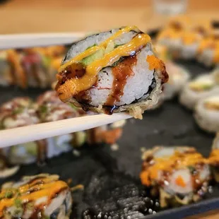 a close up of a piece of sushi being lifted by chopsticks