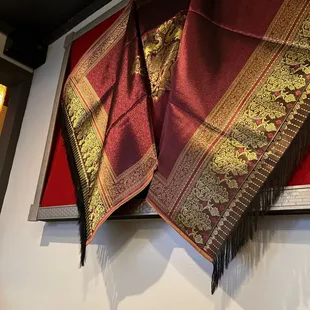 a red and gold shawl hanging on a wall