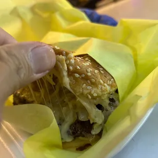 a hand holding a cheeseburger