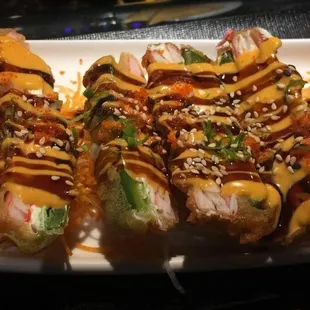 a plate of sushi with sauce and vegetables