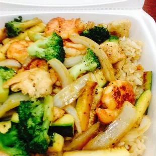 shrimp, broccoli, and cauliflower stir fry in a styrofoam container