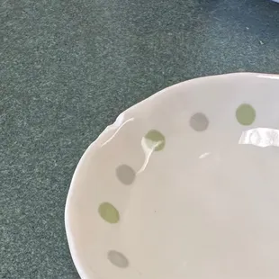 a white bowl with green polka dots