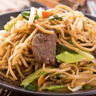 a plate of noodles with beef and vegetables