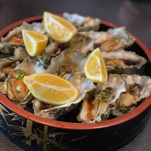 a bowl of oysters with lemon wedges