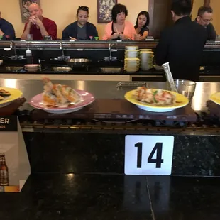 A train drives around the bar &amp; you pick up the small plates you want. $2.25 for yellow plates, $2.80 for purple plates.