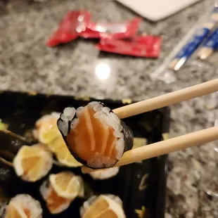 What is this? Lemon salmon roll normally has sushi rice, avocado, salmon inside and outside, cucumbers and topped with a slice lemon on top.