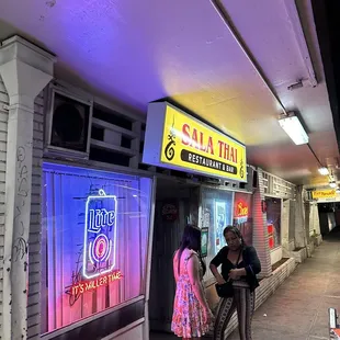 two people standing outside of a restaurant