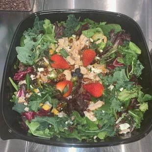 a salad with strawberries, lettuce, and nuts