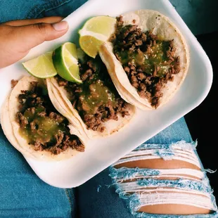 a person holding a plate of tacos