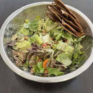 Large salad bowl with toasted pita bread.