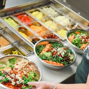 a woman preparing a salad at a buffet