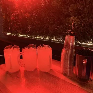 a table with three glasses and a pitcher on it